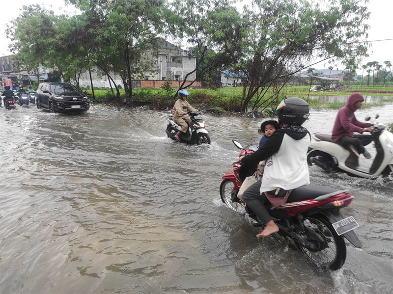 Pengendara sepeda motor melintas di Jalan Kartama yang mengalami banjir hingga menyebabkan kemacetan, Senin (24/2/2025).