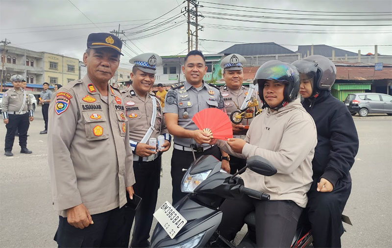 Kapolsek Rengat Barat, AKP Buha Siahaan SH (kiri) bersama personel didampingi Kepala KPR, Wandeswanda SH saat menyerahkan souvenir kepada pengendara, Selasa (25/2/2025). Foto