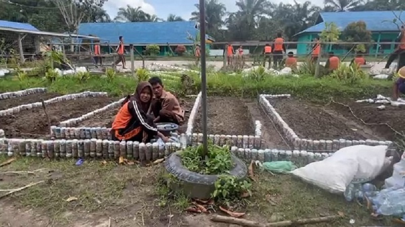 Siswa SMK Negeri 3 Dumai menata lahan pekarangan sekolah menjadi taman dengan menggunakan botol bekas kemasan.