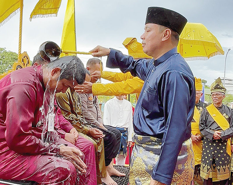 Wakil Bupati Pelalawan, H Husni Tamrin SH melakukan penyiraman air kepada Camat Pelalawan Yusman Effendi dalam prosesi adat mandi Balimau Sultan, Selasa (25/2/2025).