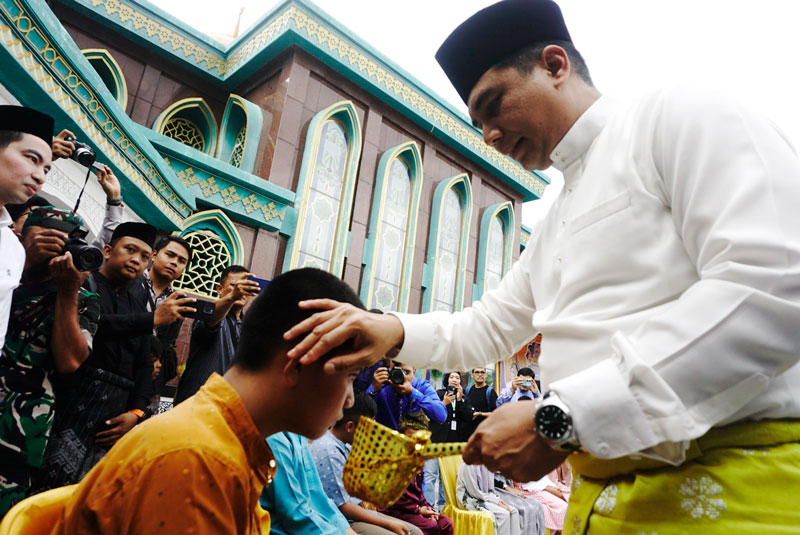 Pj Sekko Pekanbaru Zulhelmi Arifin mengusap kepala anak yatim dengan air limau saat prosesi tradisi Petang Balimau di Masjid Raya Pekanbaru, Kecamatan Senapelan, Jumat (28/2/2025).