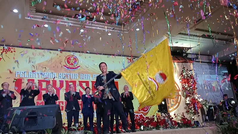 Ketua Yayasan Marga Huang Pekanbaru Djohan (depan) mengibarkan bendera pataka Yayasan Marga Huang Pekanbaru usai dilantik, Jumat (28/2/2025) malam.