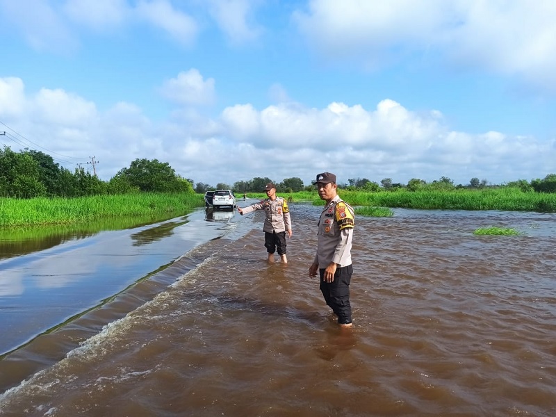 Personel Polsek Langgam memantau perkembangan banjir di Jalan Pemda Kelurahan Langgam Kecamatan Langgam dampak pembukaan pintu waduk PLTA Kota Panjang, Kampar, Senin (3/3/2025).