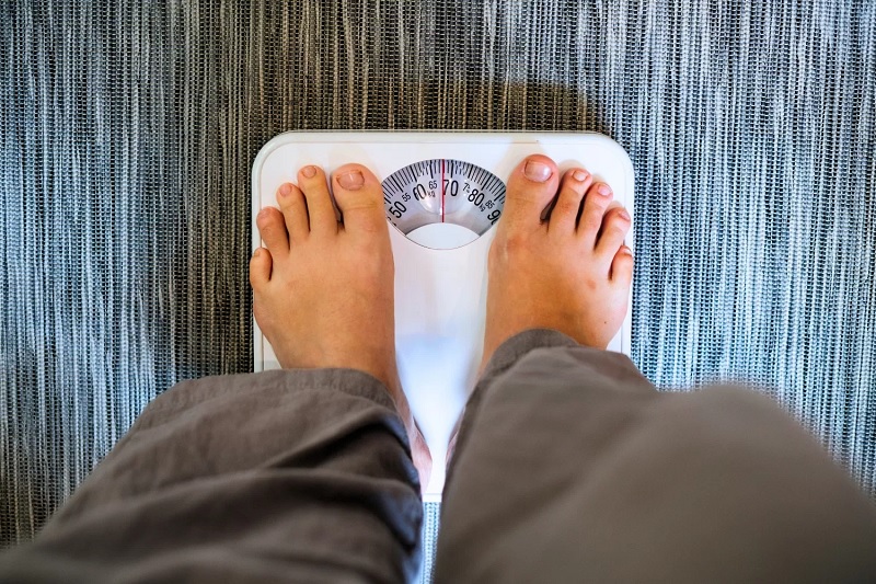 Iustrasi orang menimbang berat badan.