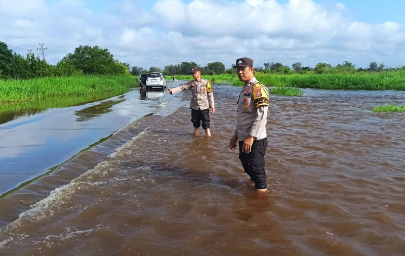 Personel Polsek Langgam memantau perkembangan banjir di Jalan Pemda, Kelurahan Langgam, Kecamatan Langgam, dampak pembukaan pintu waduk PLTA Koto Panjang.