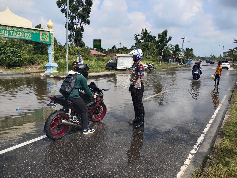 Petugas saat berjaga di lokasi banjir di Jalan Sudirman ujung, tepatnya setelah Jembatan Siak IV. Polisi mengimbau pengendara agar mencari jalan alternatif lain, Selasa (4/3/2025).