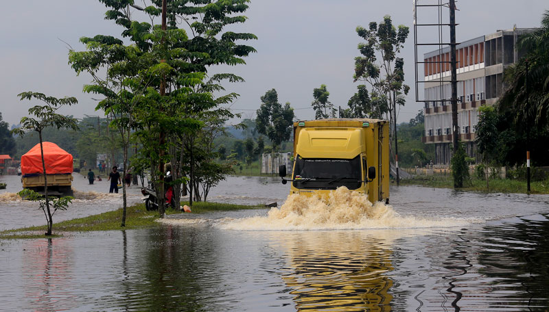 Kendaraan melewati genangan banjir air Sungai Siak di Jalan Jenderal Sudirman ujung yang kini mulai berangsur surut, Senin (10/3/2025).