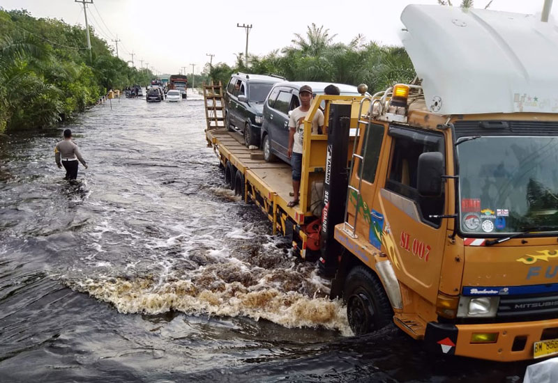 Pemilik kendaraan roda empat memanfaatkan jasa angkut mobil gendong untuk melewati Jalan Lintas Timur Km 83 Desa Kemang, Kecamatan Pangkalan Kuras, Kabupaten Pelalawan.