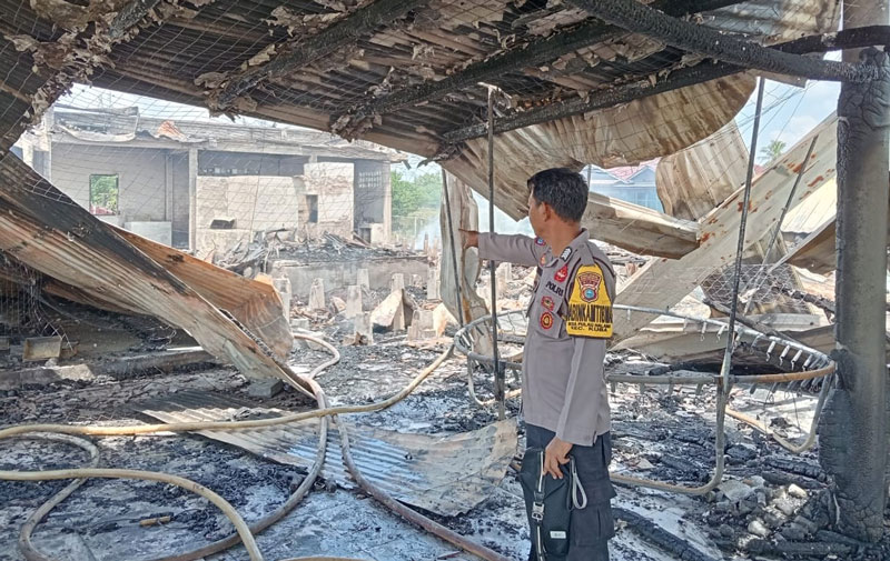 Personel polisi melihat bekas bangunan rumah dan gudang terasi yang terbakar di Kepenghuluan Pulau Halang Hulu, Kecamatan Kubu Babussalam, Ahad (16/3/2025).
