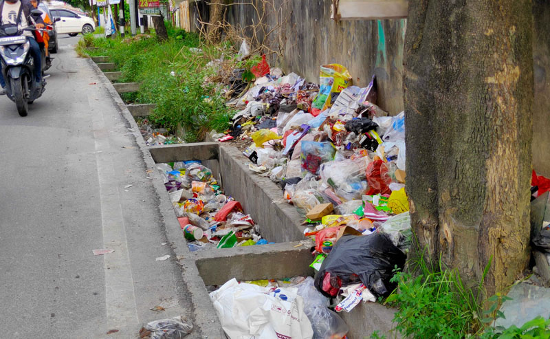Sampah menumpuk dan berserakan hingga ke dalam drainase di Jalan Dahlia, Kecamatan Sukajadi, Pekanbaru, Ahad (16/3/2025).