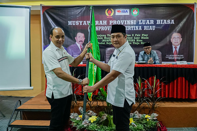 Ketua Pertina Riau 2025-2029, Doan Samuel Nababan menerima pataka dari perwakilan Pertina Pusat, Martinez Dos Santos, saat Musprovlub, di Hotel Alpha, Pekanbaru. Selasa (18/3/2025).