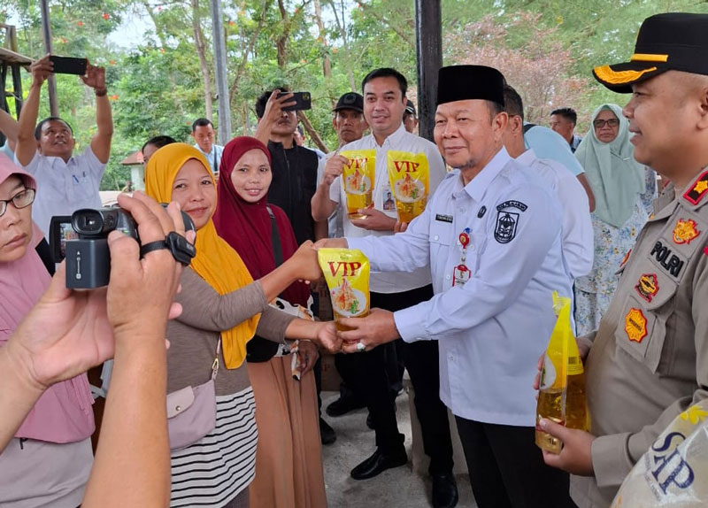 Asisten Administrasi Bidang Pembangunan dan Ekonomi Setdakab Pelalawan Drs H Fakhrizal MSi menyerahkan sembako murah kepada warga dalam operasi pasar di Kantor Camat Pangkalankerinci.