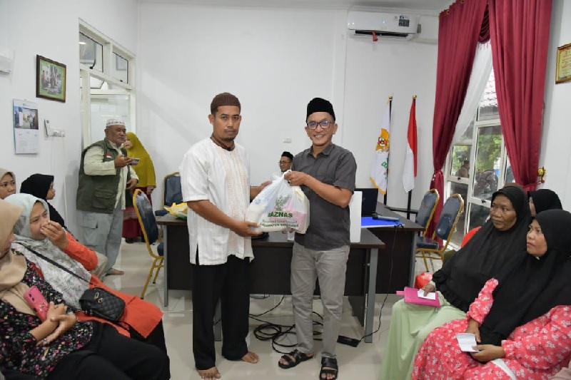 Wakil Ketua I Baznas Kabupaten Bengkalis, Risman Hambali menyerahkan bantuan ke mustahik duafa di Kantor Baznas Bengkalis, Jumat (21/3/2025) sore.