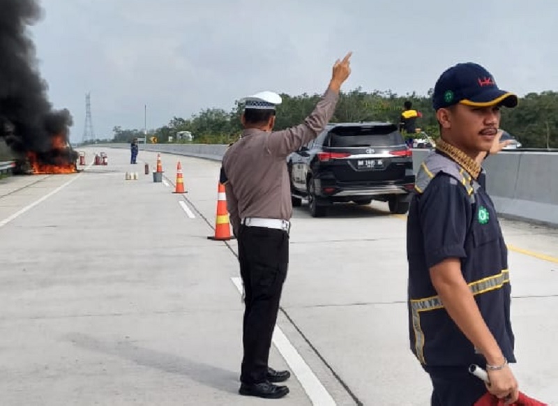 Personel Satlantas bersama personel Damkar memadamkan api yang membakar mobil SUV di jalan tol Pekanbaru-Bangkinang Km 12 A, Rabu pagi (26/3/2025).