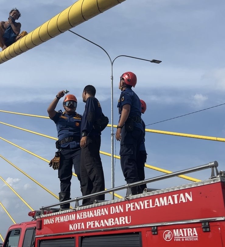 Petugas Damkar  Pekanbaru saat mengevakuasi seorang pemuda yang mencoba ingin melakukan bunuh diri dari jembatan Siak 4, Pekanbaru, Sabtu (29/3/2025).