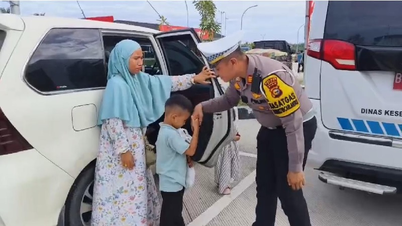 Kasatlantas Polres Siak AKP Kaliman berbincang dengan pemudik sambil memberikan minuman untuk berbuka puasa, Jumat (28/3/2025).