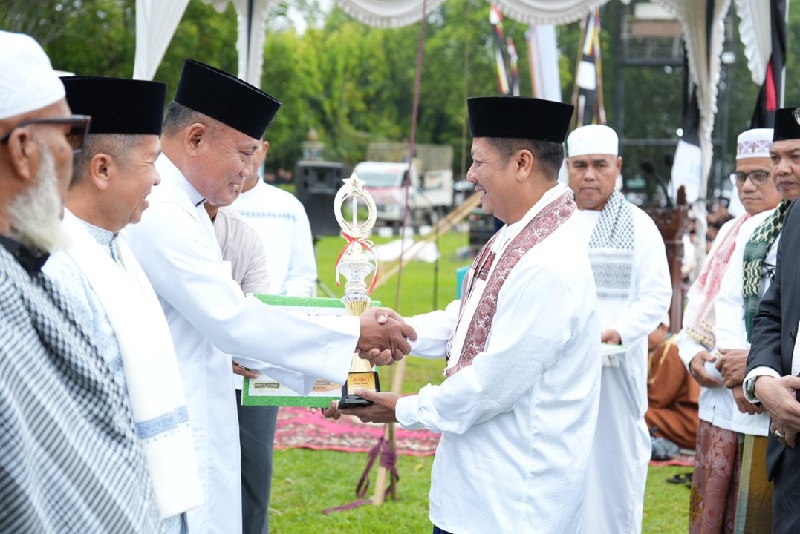 Wakil Bupati Kuansing H Muklisin menyerahkan piala juara I pada pengurus masjid Al Ikhlas Desa Sawah yang memenangi lomba pawai takbiran, Senin (31/3/2025) di Lapangan Limuno Telukkuantan.