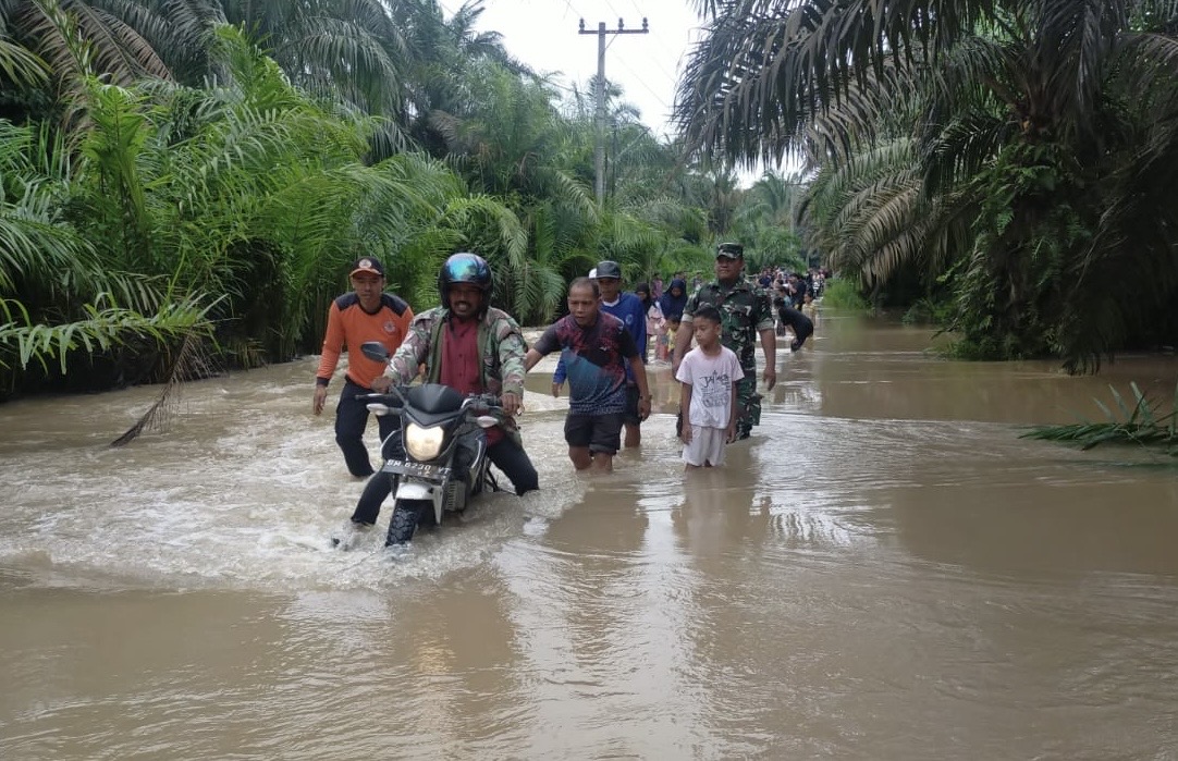 Camat Lubuk Batu Jaya, Armin membantu mendorong kendaraan warga saat melintas jalan terendam banjir, Sabtu (5/4/2025). Foto Kecamatan Lubuk Batu Jaya