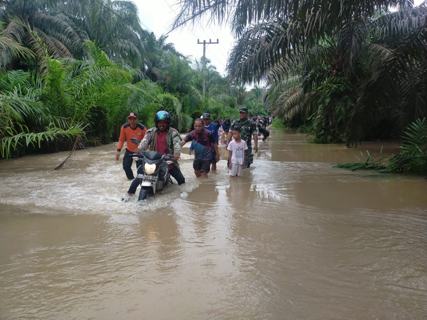 Camat Lubuk Batu Jaya, Armin membantu mendorong kendaraan warga saat melintas jalan terendam banjir, Sabtu (5/4/2025).