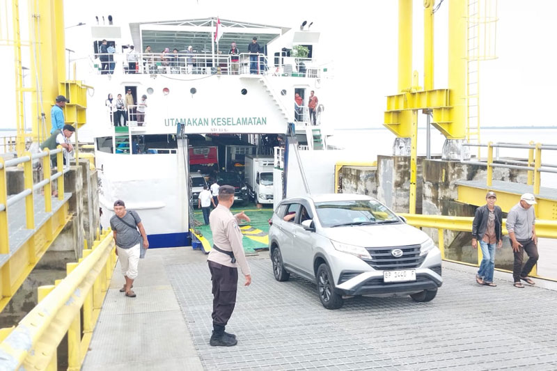 Personel Satlantas Polsek Sungai Apit me&shy;mastikan mobil dan penumpang yang keluar kapal Ro-Ro aman dan terkendali di Pelabuhan Tanjung Buton, Mengkapan, Siak, Sabtu (5/4/2025).