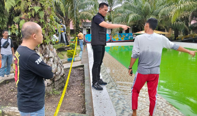 Kasat Reskrim Polres Inhil AKP Budi Winarko SH bersama personel memasang garis polisi di lokasi kejadian tenggelamnya seorang anak  di Kecamatan Tembilahan.