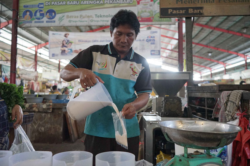 Pedagang menuangkan santan ke kantong plastik di Pasar Pagi Arengka Pekanbaru, Senin (14/4/2025).