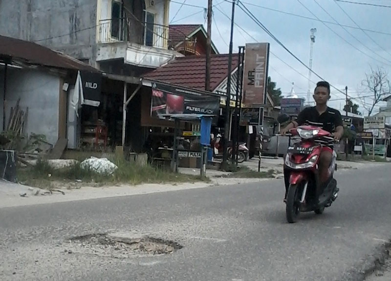 seorang pengendara melewati jalan rusak di Kota Pangkalan&shy;kerinci, beberapa waktu lalu.