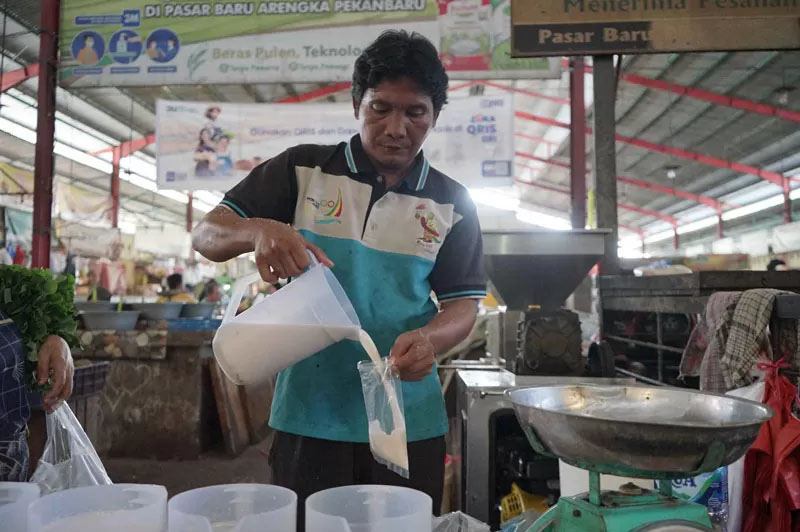 Pedagang menuangkan santan ke kantong plastik di Pasar Pagi Arengka Pekanbaru, Senin (14/4/2025).