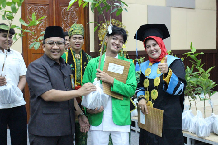 Direktur Poltekkes Kemenkes Riau, Rully Hevrialni, SST, Bdn, M.Keb, MH (kanan) berikan penghargaan berupa bibit pohon kepada mahasiswa dan pegawai Poltekes Kemenkes Riau yang berprestasi, Rabu (16/4)