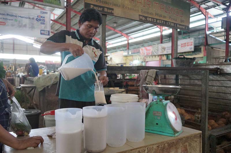 Pedagang menuangkan santan ke kantong plastik di Pasar Pagi Arengka Pekanbaru, Senin (14/4/2025).