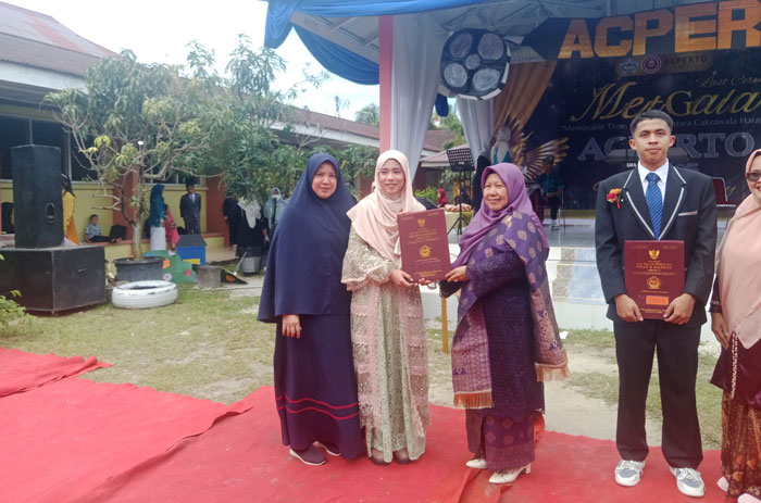 Kepala SMAN 2 Mandau Dra Hj Lismawati menyerahkan buku rapor kepada siswanya saat menggelar perpisahan siswa di halaman SMAN 2 Mandau, Kamis (17/4/2025).