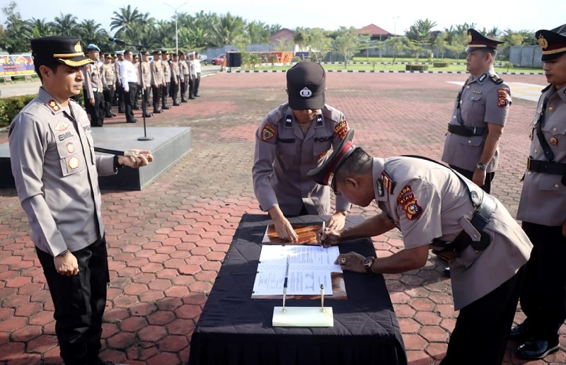 Kapolres Rohul AKBP Emil Eka Putra SIK SH MSi menyaksikan Kapolsek Rambah AKP Yani Marjono secara bergantian dengan Kasat Intelkam menandatangani berita acara sertijab dalam upacara di lapangan.