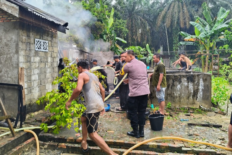Kapolsek Tapung Hilir AKP Toni SH MH bersama personel Polsek Tapung Hilir dibantu warga berjibaku memadamkan api yang membakar sebuah rumah Sarto warga Desa Kota Bangun.