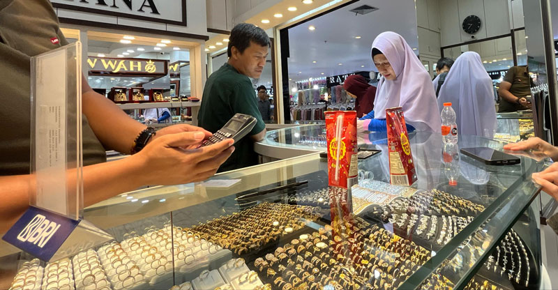 Seorang pedagang emas sedang melayani pembeli yang melihat produk perhiasan emas di Sukaramai Trade Center, Pekanbaru, Selasa (22/4/2025).