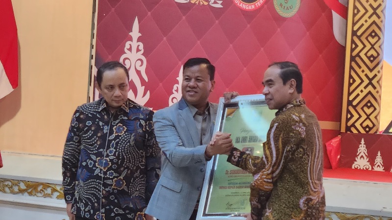 Ketua Ikatan Alumni Universitas Riau, Wan Muhammad Hasyim menyerahkan penghargaan  alumni terfavorit kepada Bupati Kuansing, Dr H Suhardiman Amby MM di Reuni Akbar, Jumat (25/4/2025).