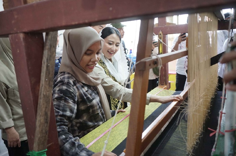 Wakil Menteri Perdagangan Dyah Roro Estu Widya Putri mencoba alat pembuatan tenun nonmesin di Tenun Wan Fitri Jalan Kayu Mas Kecamatan Payung Sekaki Pekanbaru, Senin (28/4/2025).