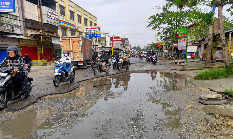 Pengendara roda dua menghindari lubang-lubang di Jalan Dharma Bakti, Kecamatan Payung Sekaki, Pekanbaru yang mengalami kerusakan parah, Selasa (29/4/2025).