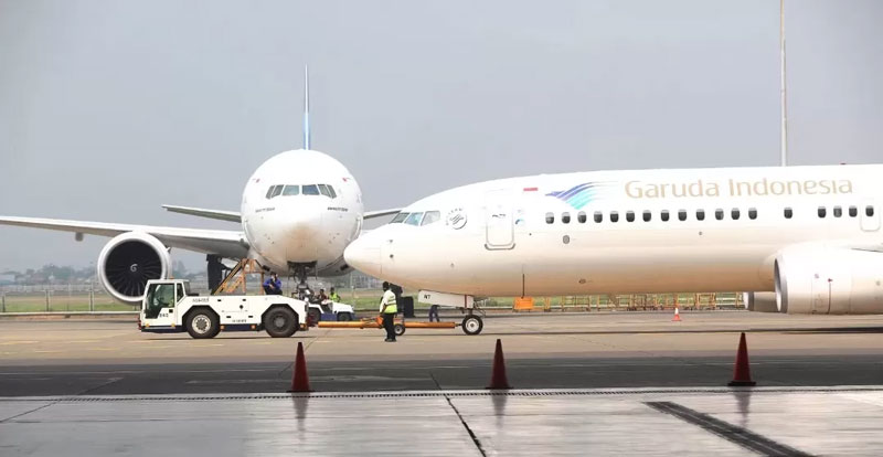 Pesawat Garuda Indonesia sedang memuat barang penumpang di bandara.