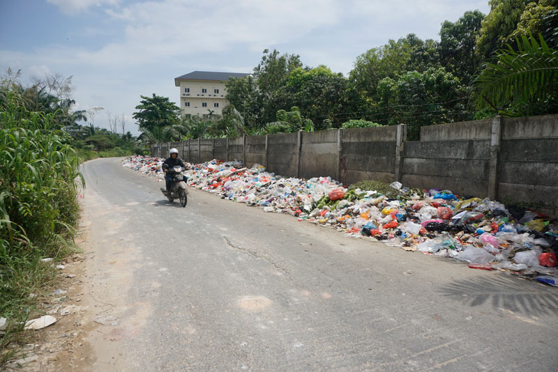 Seorang pengendara melewati Jalan Laos, Kecamatan Payung Sekaki , persisnya di dekat lokasi tumpukan sampah, Kamis (8/5/2025) siang.