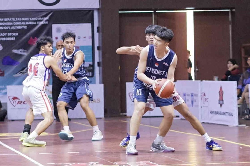 Pemain SMA Metodis Medan Gablin (dongker) mempertahankan bola ketika diadang pemain SMAN 2 Bandung saat pertandingan Turnamen Rajawali Cup III 2025 di GOR Tribuana Pekanbaru, Ahad  (11/5/2025).
