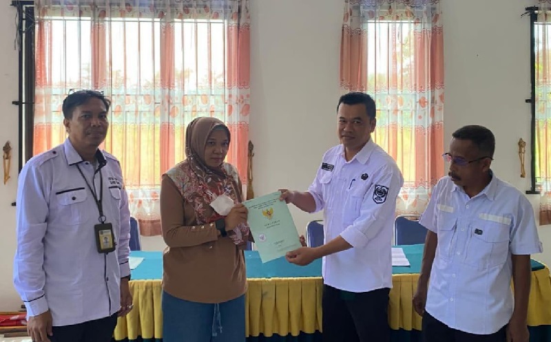 Kepala Seksi Tata Pemerintahan Afri Candra menyerahkan sertifikat PTSL kepada Rifda Yunita disaksikan bersama Kepala Seksi (Kasi) Pendataan Tanah Kantor Pertanahan (Kantah) Siak Martheen Miharja .
