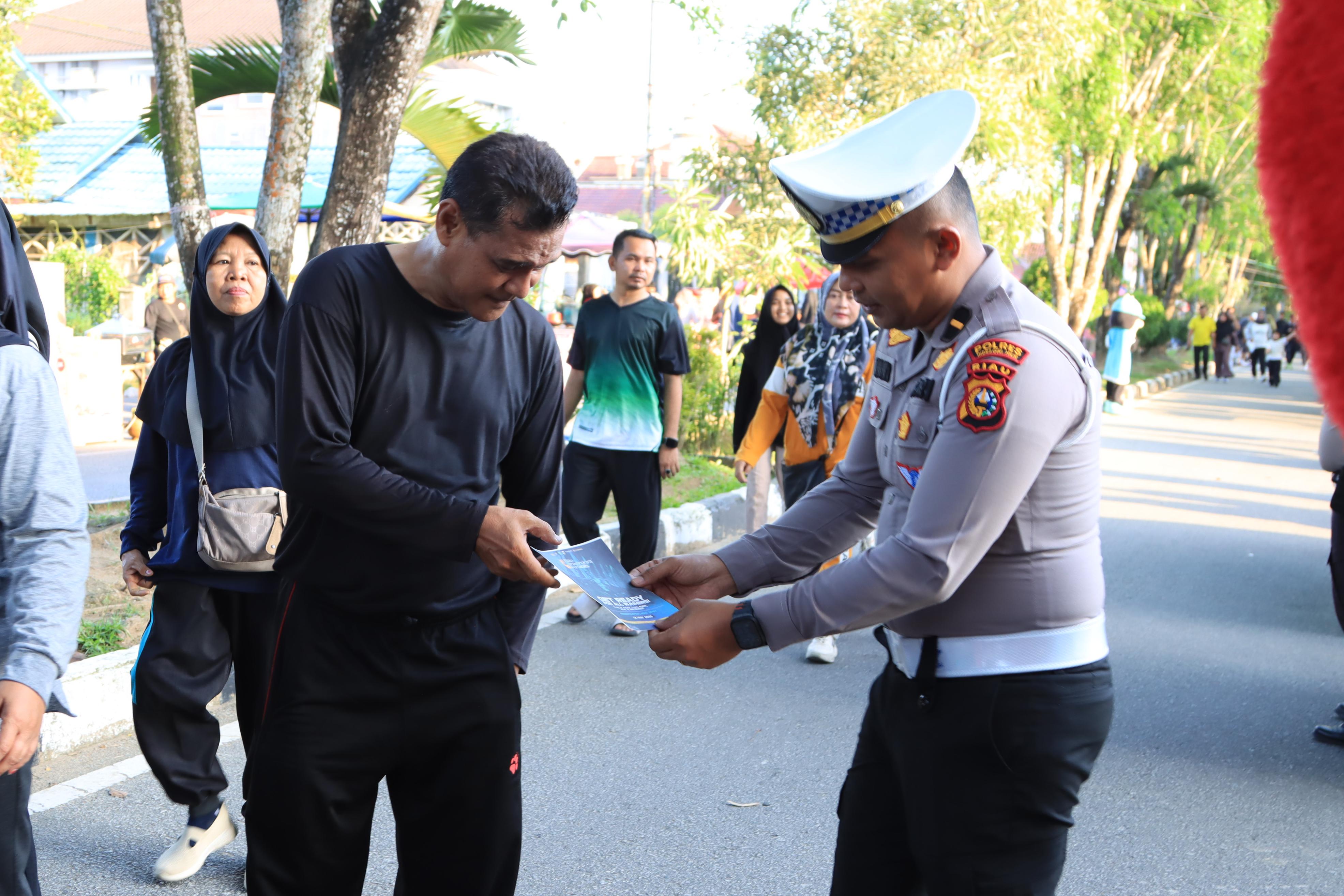 Salah seorang Personel Satalntas Polres Inhil Iptda Jimy Lano, membagikan brosur kepada salah seorang pengunjung CFD, Ahad (18/5/2025).