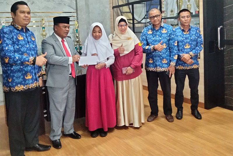 Kadisdikpora Kabupaten Kampar Aidil menyerahkan bonus kepada Aqila Azzahra di ruang kerja Kadisdikpora Kabupaten Kampar, Bangkinang, Selasa (20/5/2025).