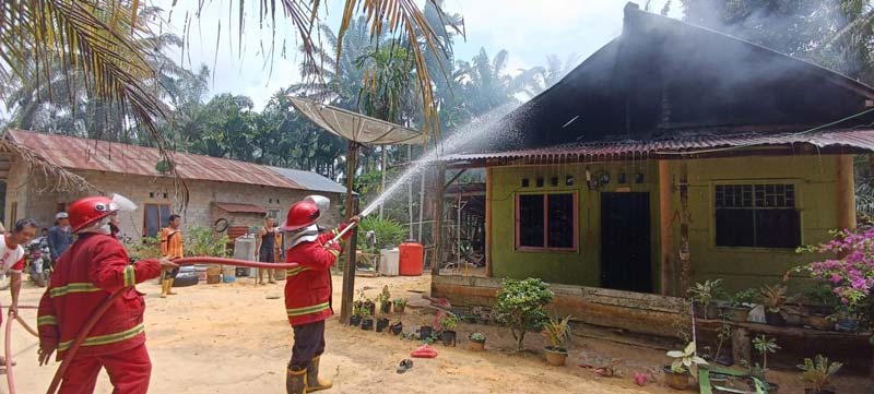 Personel Unit Damkar Kecamatan Bagan Sinembah saat memadamkan api yang membakar rumah di Kepenghuluan Gelora, Kecamatan Bagan Sinembah, Senin (19/5/2025)