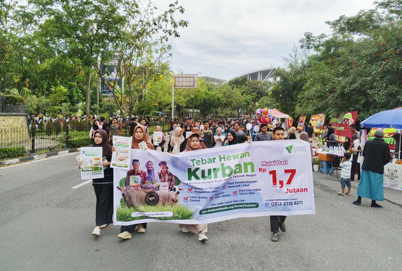 Peserta melakukan longmarch kurbanaval Dompet Dhuafa Riau dengan membentangkan spanduk tebar hewan kurban mengelilingi area car free day Pekanbaru