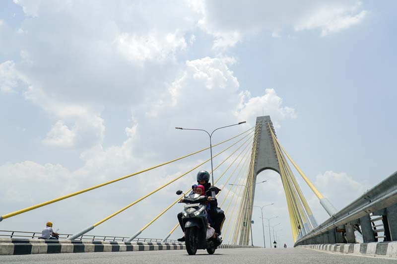 Pengendara sepeda motor melintasi Jembatan Sultan Abdul Jalil Alamuddin Syah, Pekanbaru, dalam kondisi cuaca panas&nbsp;terik, Selasa (27/5/2025).