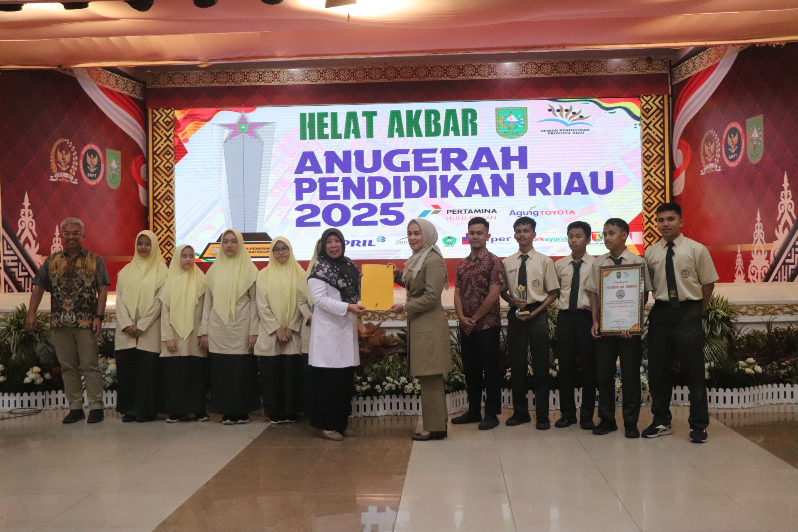 Kepala MAN 1 Kota Pekanbaru Norerlinda MPd menerima piagam  penghargaan  anugerah terbaik 1 ekskul pilihan 2025 unit kegiatan Robotik dari anggota DPR RI Karmila Sari, Selasa  (27/