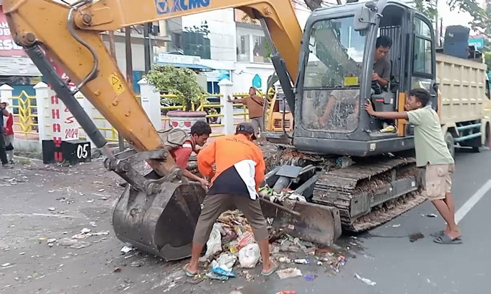 Petugas gabungan melakukan pengerukan sampah di jalan jendral Sudirman menggunakan alat berat, Ahad (8/6/2025).