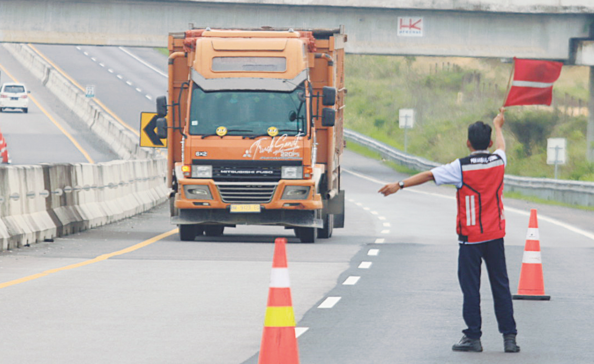 Petugas memberikan arahan kepada sopir truk yang melintas di Tol Pekanbaru-Dumai, Ahad (8/6/2025).