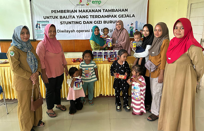 PR CSR Officer EMP Energi Riau, Sri Hartati saat menyerahkan bantuan makan kepada selah seorang balita, Selasa (10/6/2025.